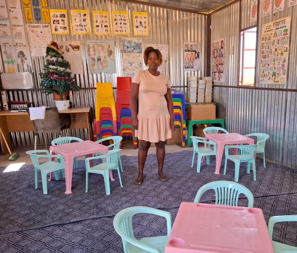 A teacher stands ready inside a colourfully decorated classroom.