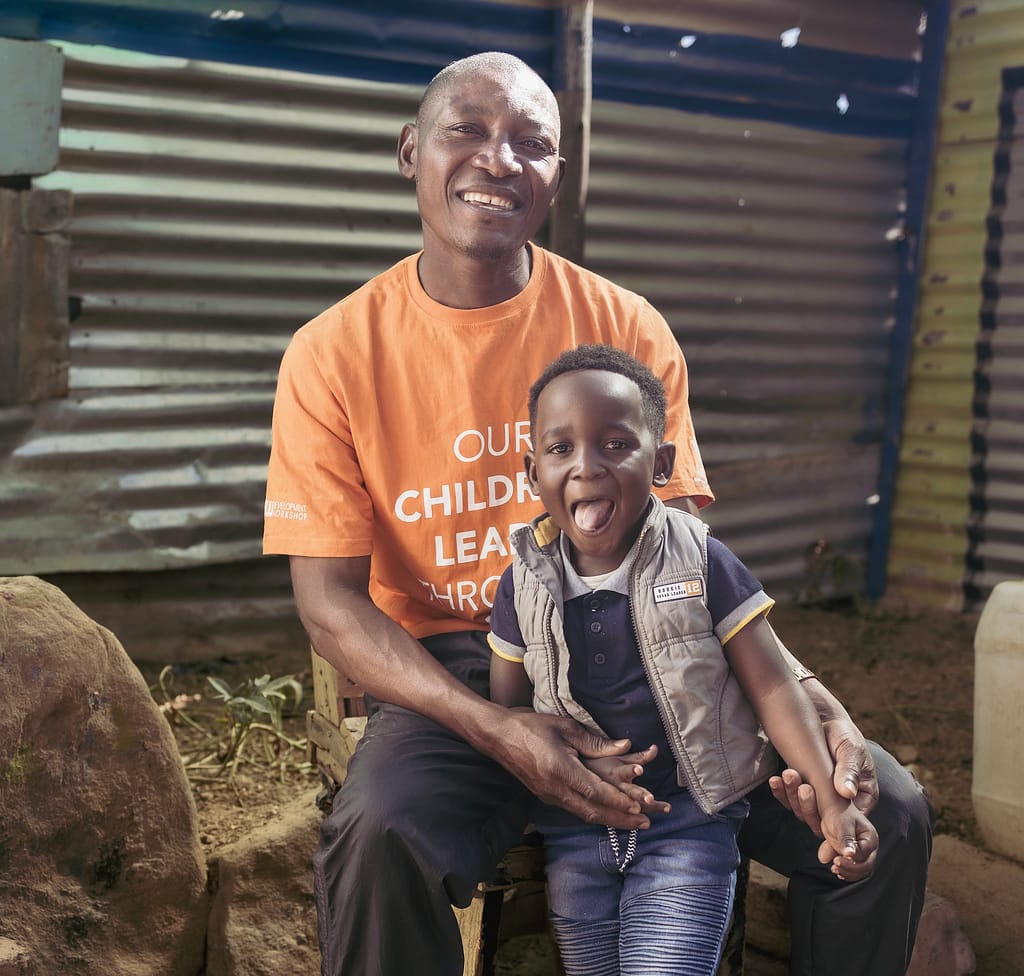 A smiling man sitting with a happy looking child.