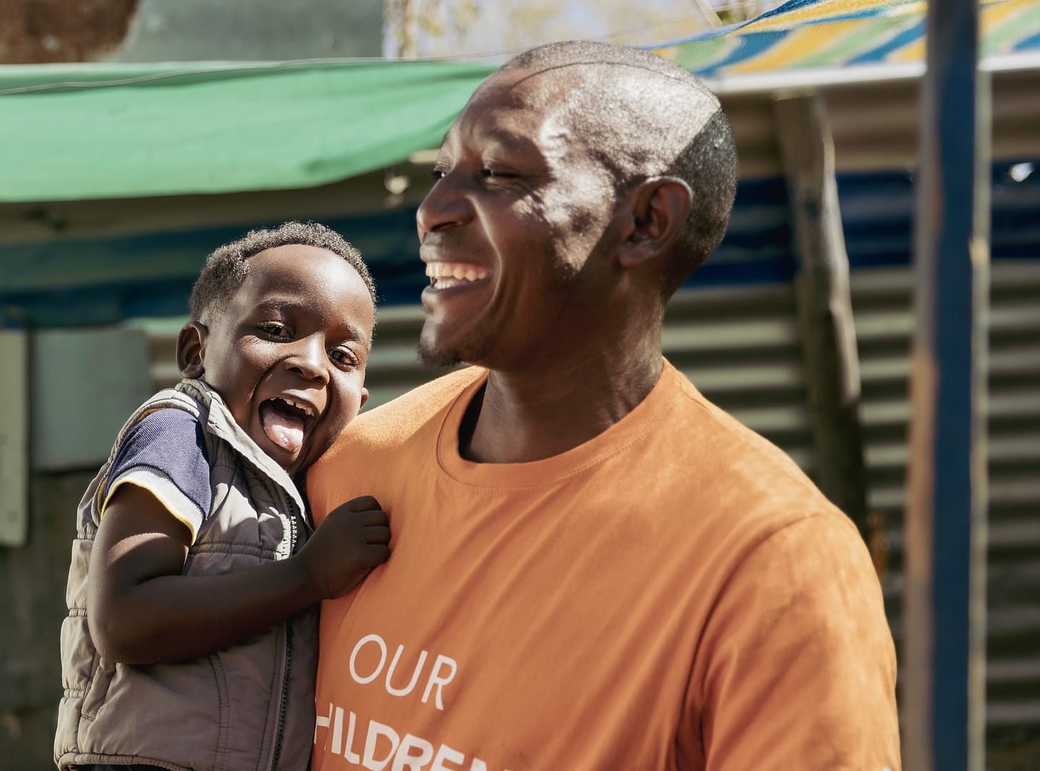 A smiling man holds a smiling child.